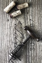 Old corkscrew with wine corks on a wooden board