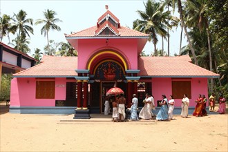 A group of women with offerings and a priest circling a Hindu temple