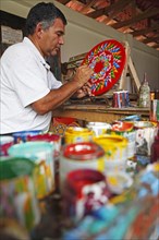 Man painting the hub of a traditional oxcart or Carreta
