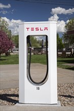 A Tesla Supercharger in the parking lot of a motel