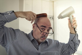 Bald man with a comb and a hair dryer hairdressing