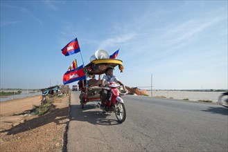 Cambodian monks and novices on a tuktuk with Buddhist flags and national flags of Cambodia at a protest