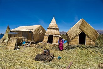 Woman of the Uro Indians in front of typical reed huts