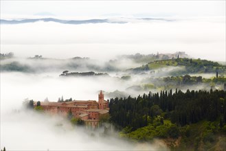 Monte Oliveto Maggiore abbey with mist-shrouded valleys