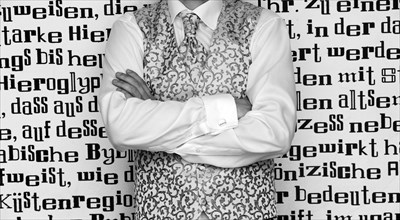 Groom wearing a tie and a waistcoat standing in front of wall with lettering