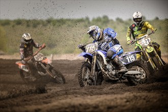 Three motocross riders on a track during a race