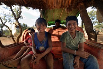 Indigenous children sitting on an old sofa in the shade