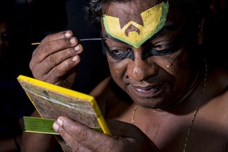 Katakali artist applying the makeup of the Deshen character