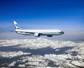 Cathay Pacific Boeing 777-367 ER in flight over mountains