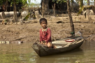 Boy sitting in a traditional boat on the Sangker river in Battambang