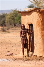 Young Himba in front of her hut