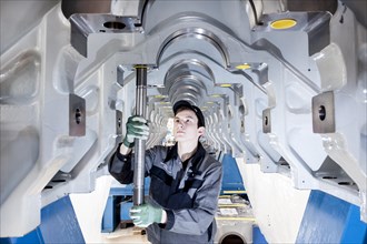 Employee fitting a tension rod into the engine frame of a marine engine