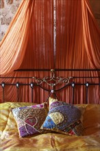 Romantic metal bed with canopy and two oriental silk cushions
