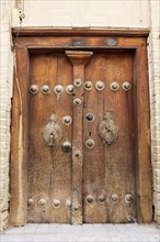 Old wooden door with different door knockers for male and female visitors