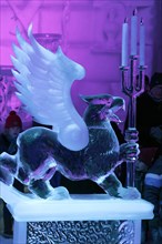 Griffin figure made of ice holding candlesticks made of ice