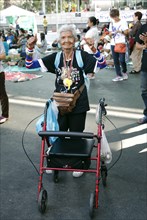 Old woman with a wheeled walker dancing amongst the protesters