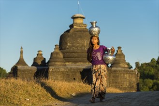 Girl with tanaka in her face carries water vessels made of aluminum