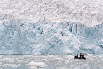 Tourists in a rubber dinghy in front of the rim of the Monacobreen Glacier