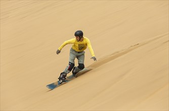 Sand boarding in the dunes of the Namib Desert