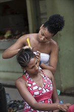 A woman dressing a girlfriend's hair