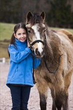 Girl standing beside a pony