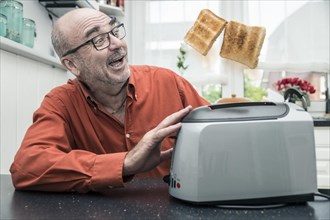Man watching 2 slices of toast being ejected from a toaster
