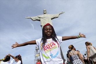 Young woman from Mozambique with her arms outstretched in front of the Christ the Redeemer statue