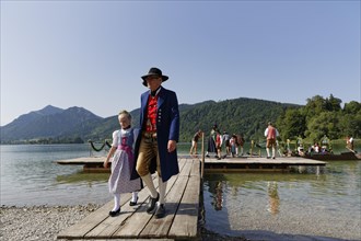 Locals wearing traditional costumes disembarking a boat at a jetty