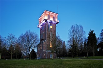 The illuminated Hammerkopfturm tower of Zeche Erin Colliery at dusk
