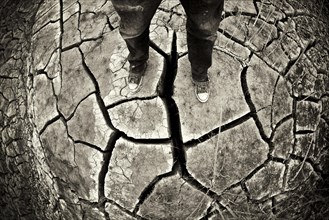Person standing on dry cracked ground in a dried stream bed during a desert drought