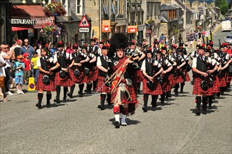 Pipe major leading a pipe band marching in unison through the town
