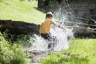 Boy jumping into a stream