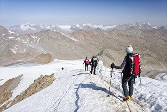 Mountain climbers descending from Similaun Mountain along the summit ridge of Niederjochferner Glacier in Schnalstal valley