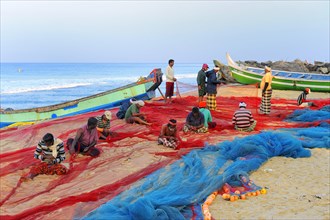 Fishermen repairing nets on the beach