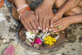 The hands of a man and a boy are placed over human bones during Dashkriya or Asthi Visarjan