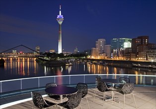 Restaurant terrace with Rheinturm tower and the Gehry buildings at the blue hour
