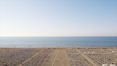 View of a beach with sunshades and sun beds at sunrise