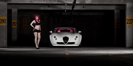 Woman with pink hair and tattoos standing next to a white sports car