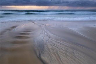 Water flows over bizarre structures on the sandy beach