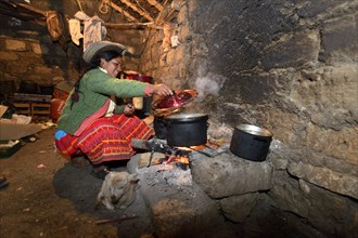 Young woman cooking on an open fire in her traditional kitchen