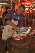 Butcher cutting pork belly with a large Chinese knife