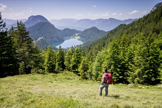 Female hiker observing the view from the Wilder-Kaiser-Steig hiking trail towards Lake Hintersteiner See