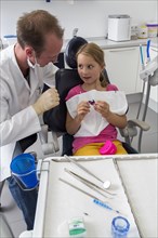 Dentist discussing further treatment with a girl and showing her braces