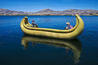 Two local people rowing a traditional boat made of totora reeds on Lake Titicaca