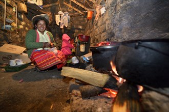 Young woman cooking on an open fire in her traditional kitchen