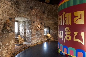 Room with a Tibetan prayer wheel and Buddha statues