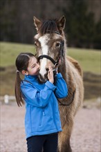 Girl cuddling with a pony
