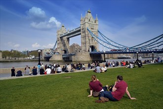 Tourists relaxing in Potters Fields Park in front of Tower Bridge