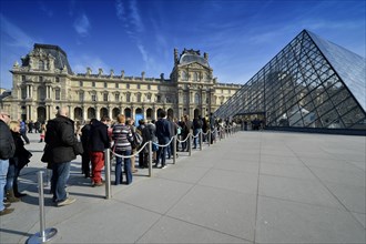 Queue in front of the entrance pyramid of the Louvre Museum designed by architect IM Pei