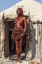 Young Himba woman standing in front of her hut